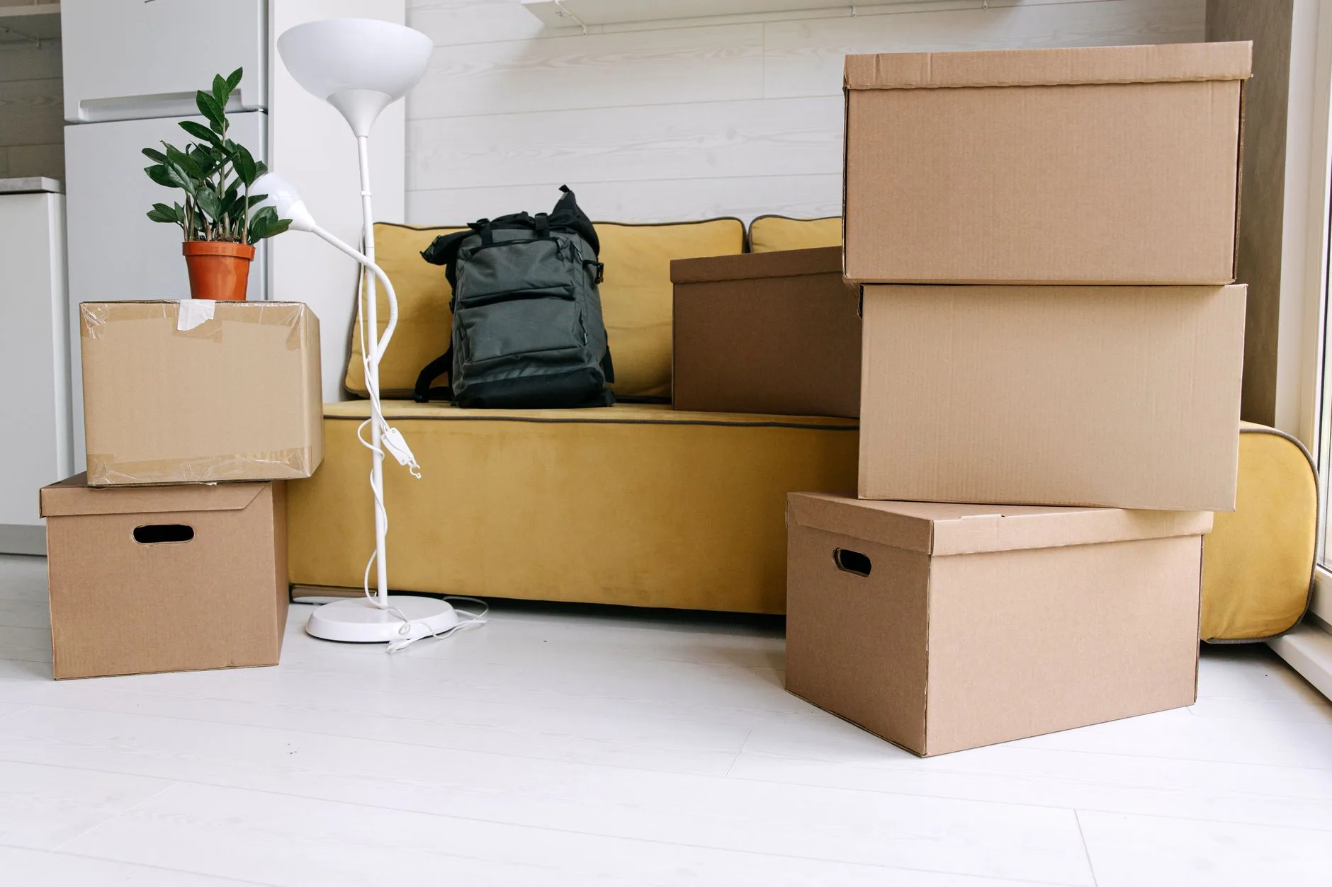 Cartons de déménagement empilés à côté d'un canapé dans un logement clair